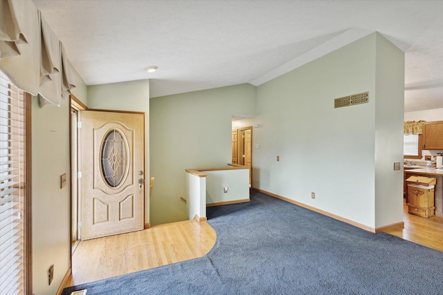 foyer entrance featuring carpet flooring and lofted ceiling