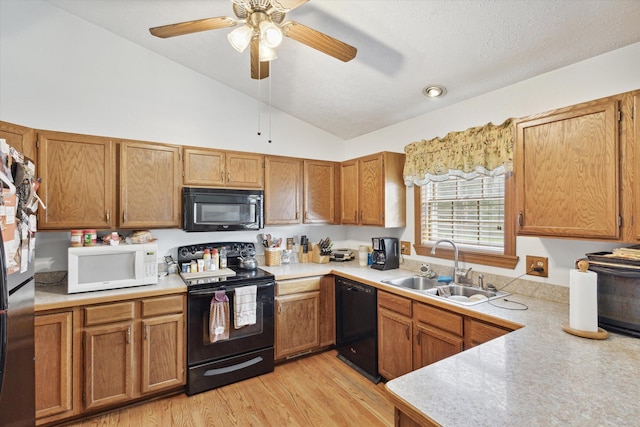 kitchen with light wood-type flooring, vaulted ceiling, ceiling fan, sink, and black appliances