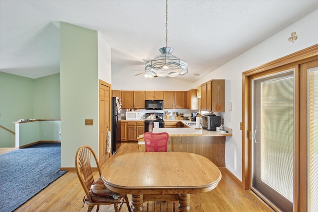 dining room featuring ceiling fan, vaulted ceiling, and light wood-type flooring