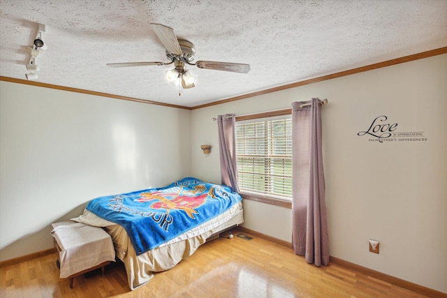 bedroom featuring hardwood / wood-style floors, ceiling fan, ornamental molding, and a textured ceiling