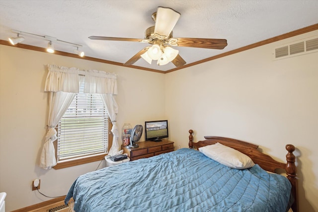 bedroom featuring ceiling fan, a textured ceiling, and ornamental molding