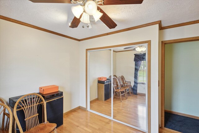 living area with a textured ceiling, wood-type flooring, and ornamental molding