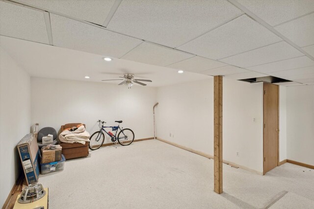 basement with a paneled ceiling, ceiling fan, and carpet