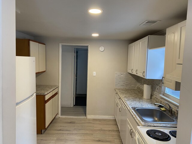 kitchen featuring sink, white cabinets, light hardwood / wood-style floors, and white appliances