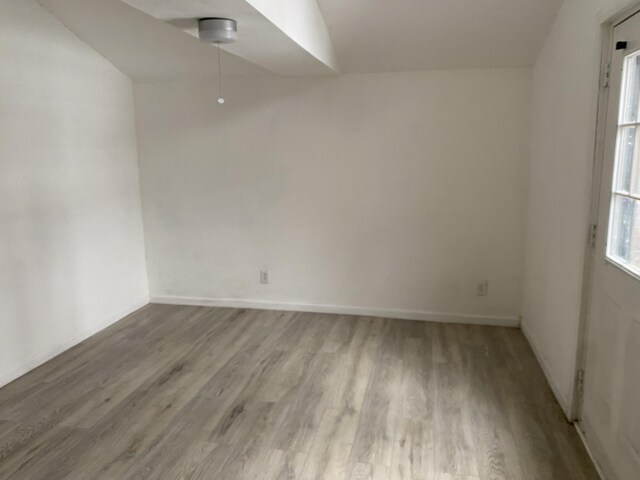 empty room featuring light hardwood / wood-style floors and vaulted ceiling