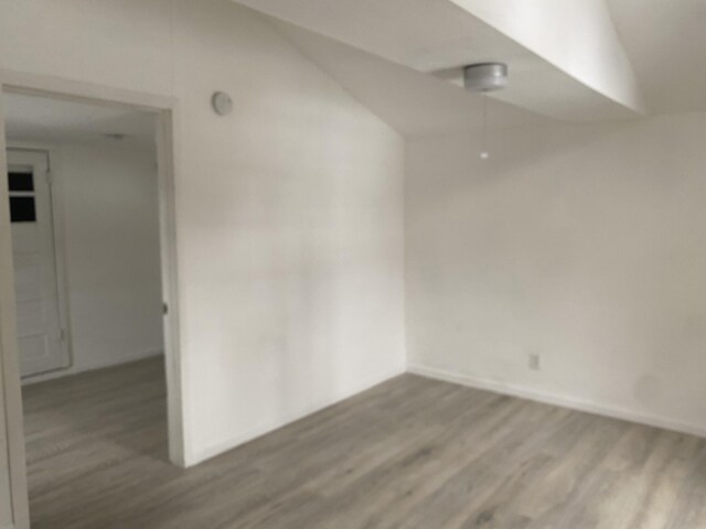 unfurnished room featuring hardwood / wood-style flooring and lofted ceiling