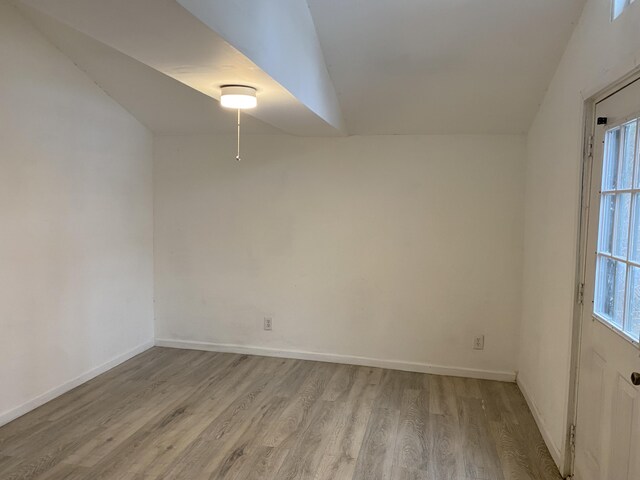 empty room featuring light wood-type flooring and vaulted ceiling