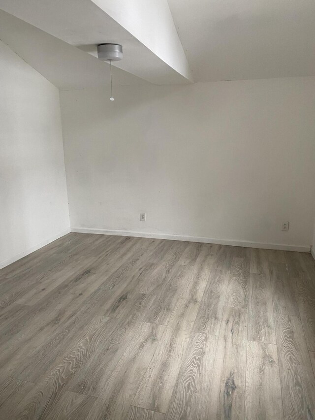 unfurnished room featuring vaulted ceiling and light wood-type flooring