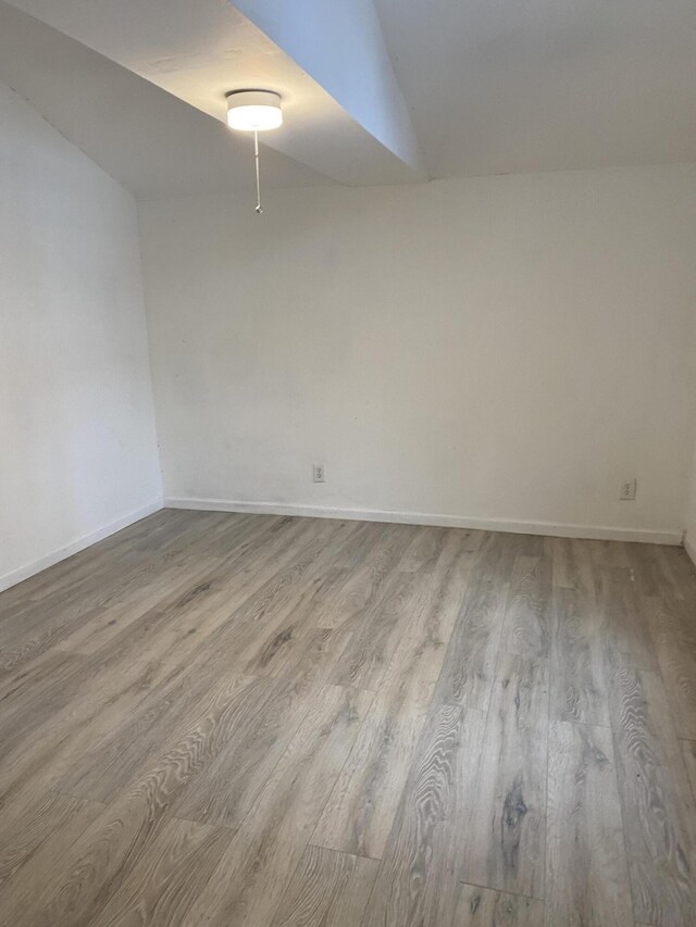 empty room featuring light hardwood / wood-style flooring and vaulted ceiling