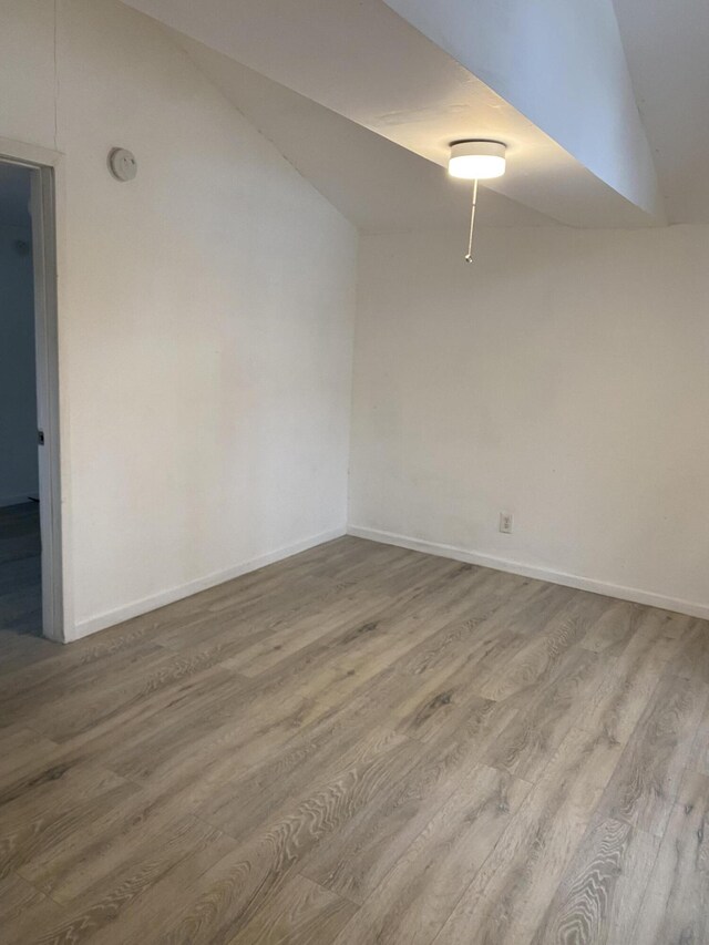 spare room with light hardwood / wood-style flooring and vaulted ceiling