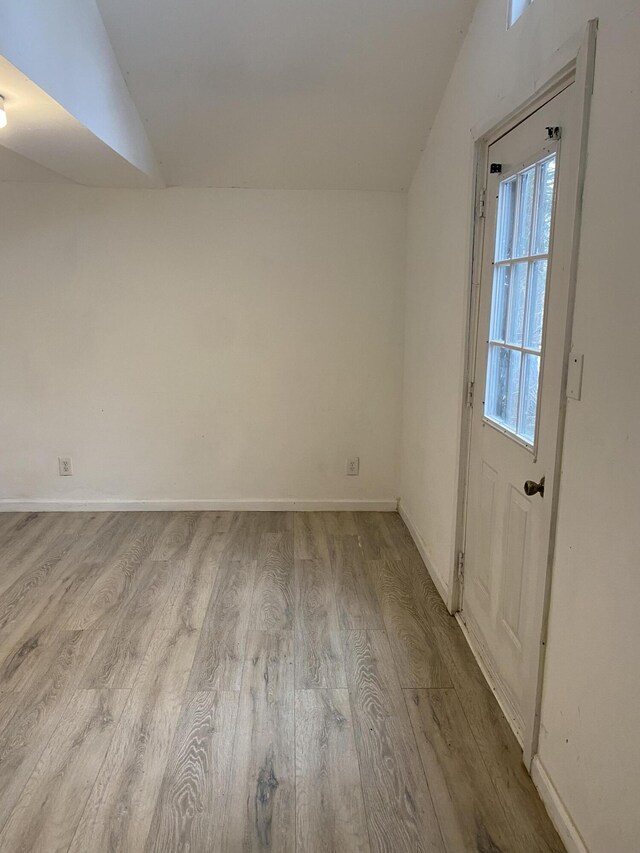 unfurnished room featuring lofted ceiling and light wood-type flooring