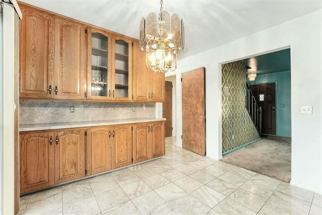 kitchen featuring backsplash, light carpet, pendant lighting, and a notable chandelier