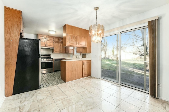 kitchen featuring an inviting chandelier, kitchen peninsula, pendant lighting, light tile patterned floors, and appliances with stainless steel finishes