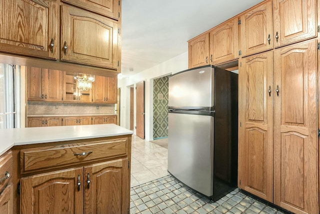 kitchen with an inviting chandelier, stainless steel refrigerator, and light tile patterned flooring