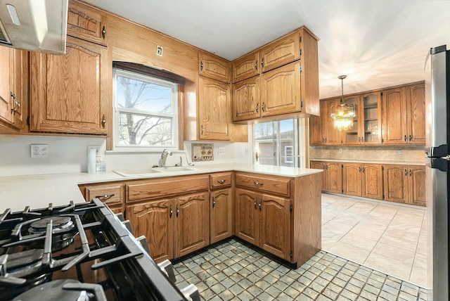 kitchen with stainless steel refrigerator, sink, kitchen peninsula, decorative light fixtures, and light tile patterned floors