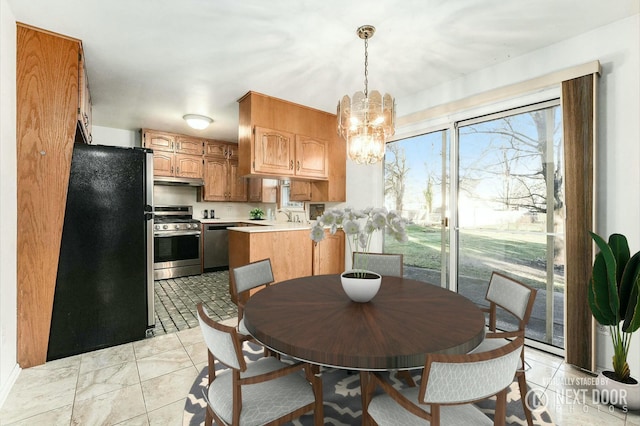 kitchen featuring a chandelier, pendant lighting, stainless steel appliances, and sink