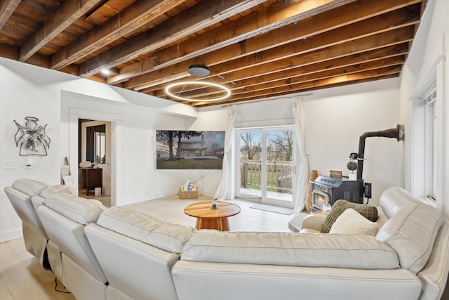 living room featuring beam ceiling, light hardwood / wood-style floors, a wood stove, and wood ceiling