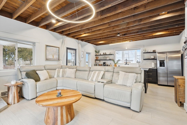 living room featuring beam ceiling, light wood-type flooring, plenty of natural light, and wood ceiling