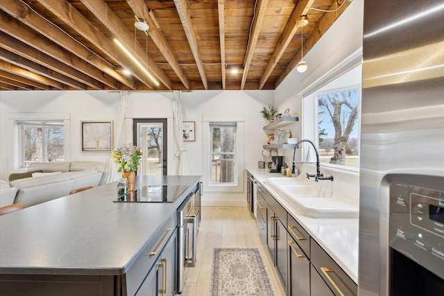 kitchen featuring beam ceiling, a center island, light hardwood / wood-style flooring, black electric stovetop, and wood ceiling