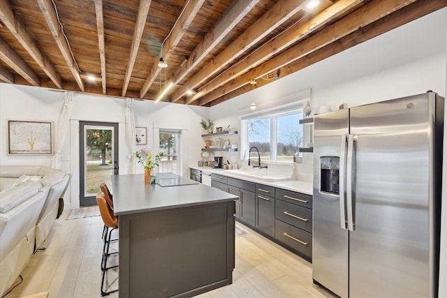 kitchen with wood ceiling, sink, beam ceiling, stainless steel fridge with ice dispenser, and a center island