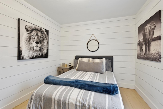 bedroom featuring light hardwood / wood-style floors and wooden walls