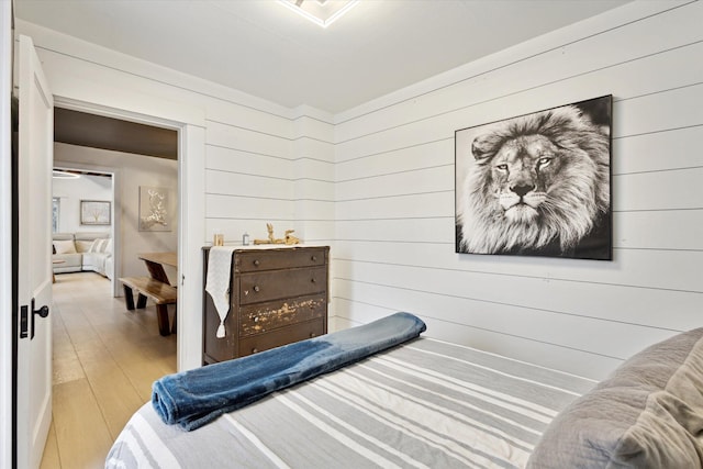 bedroom with wood walls and light hardwood / wood-style flooring