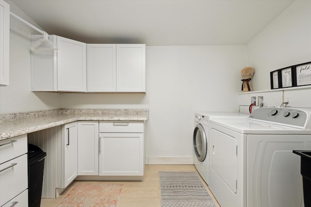 clothes washing area with light hardwood / wood-style floors, cabinets, and separate washer and dryer