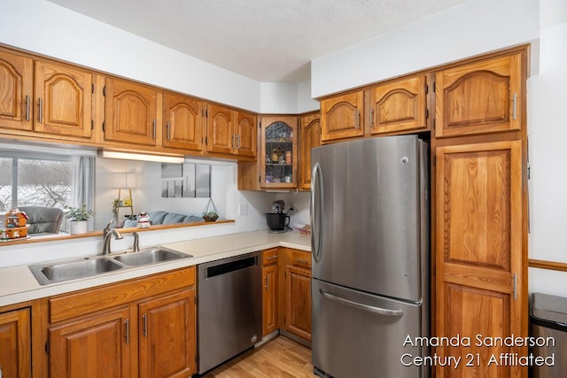 kitchen featuring sink, light hardwood / wood-style flooring, a textured ceiling, and appliances with stainless steel finishes