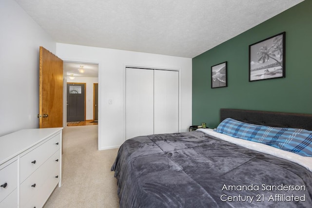 bedroom with a closet, light colored carpet, and a textured ceiling