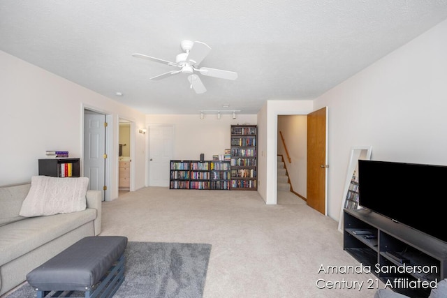 carpeted living room with a textured ceiling, rail lighting, and ceiling fan