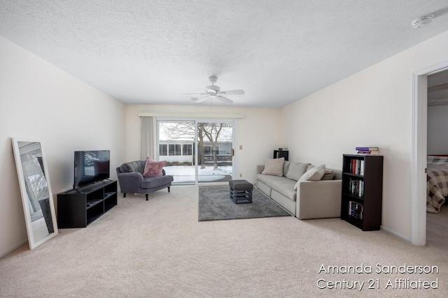 carpeted living room featuring ceiling fan and a textured ceiling