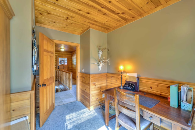 office area featuring wood walls, wooden ceiling, and light carpet