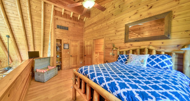 bedroom with ceiling fan, light hardwood / wood-style flooring, wooden ceiling, beamed ceiling, and wood walls