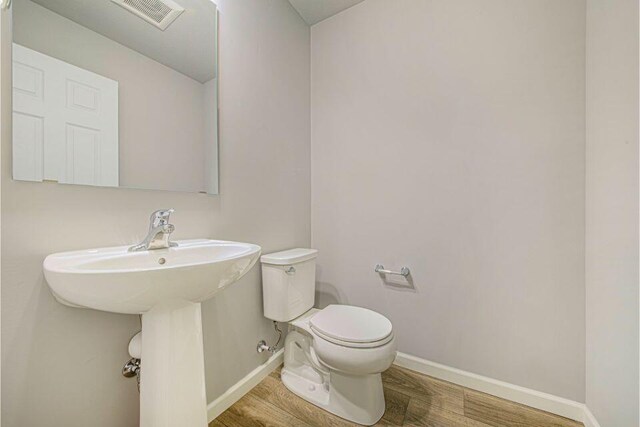 bathroom featuring wood-type flooring and toilet