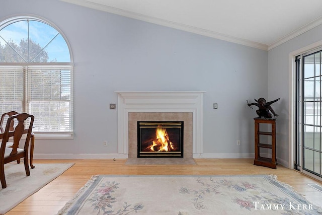 living room featuring lofted ceiling, light wood-type flooring, crown molding, and a tile fireplace