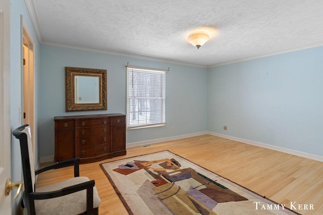 living area featuring a textured ceiling, light wood-type flooring, and crown molding