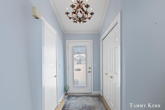 entryway with crown molding and a chandelier