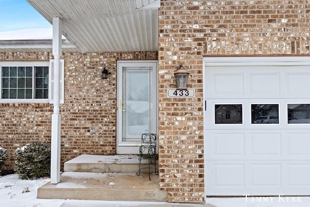 snow covered property entrance with a garage