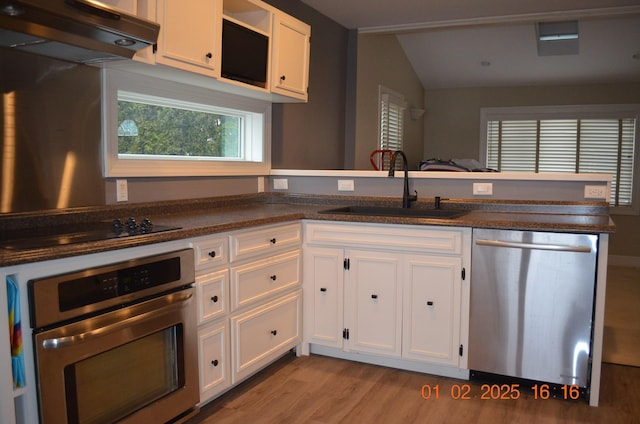 kitchen featuring appliances with stainless steel finishes, white cabinetry, sink, kitchen peninsula, and light wood-type flooring