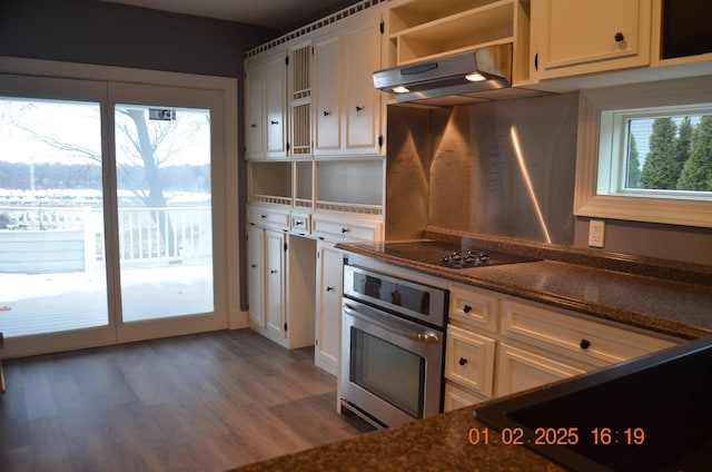 kitchen with white cabinetry, black electric stovetop, stainless steel oven, dark wood-type flooring, and dark stone counters