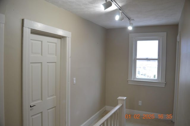 hallway with a textured ceiling and track lighting