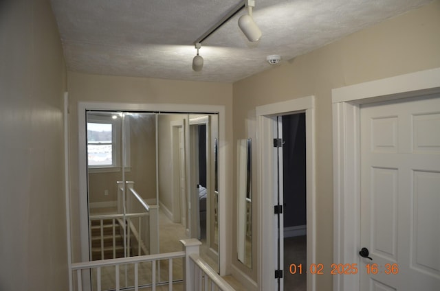 hall with a textured ceiling and rail lighting