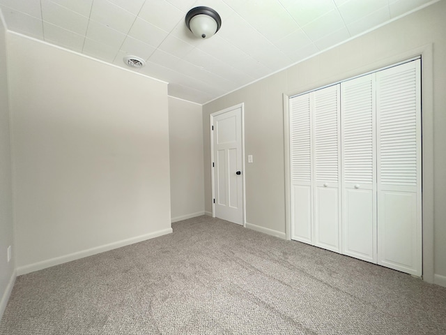 unfurnished bedroom featuring light colored carpet and a closet