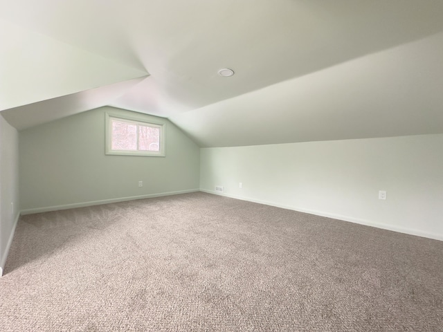 additional living space featuring lofted ceiling and carpet flooring