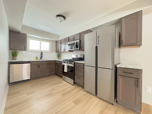 kitchen with light hardwood / wood-style flooring, stainless steel appliances, tasteful backsplash, dark brown cabinets, and sink