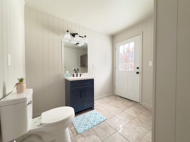 bathroom featuring toilet, wood walls, tile patterned floors, and vanity