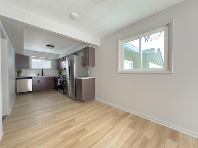 kitchen featuring stainless steel appliances, sink, tasteful backsplash, light hardwood / wood-style flooring, and dark brown cabinets