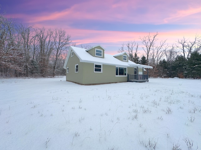 snow covered back of property with a porch