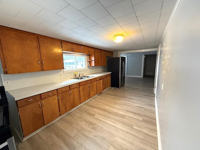 kitchen featuring stainless steel fridge, light wood-type flooring, and sink