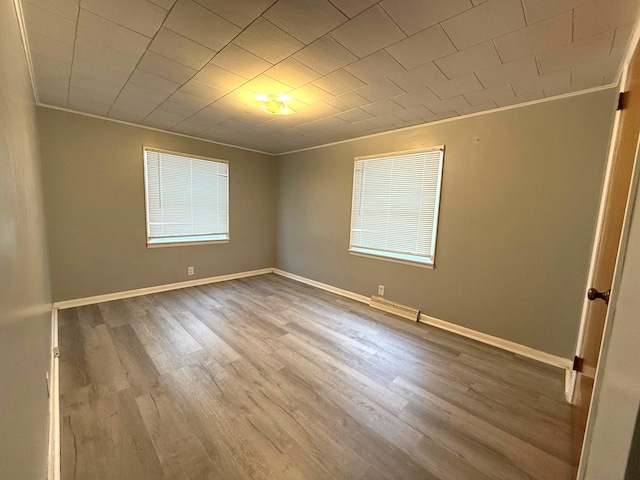 spare room with hardwood / wood-style flooring and crown molding